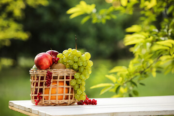 Wicker basket with fresh fruits on table outdoors