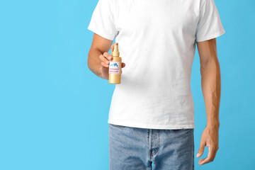 Young man with mosquito repellent on color background