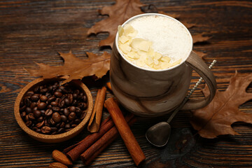 Cup of tasty almond latte and coffee beans on wooden background