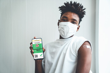 African American teenager shows vaccine passport on mobile phone to validate travel permission by...