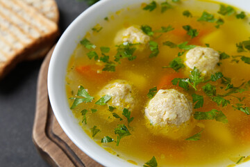 Bowl with tasty meatball soup on dark background, closeup