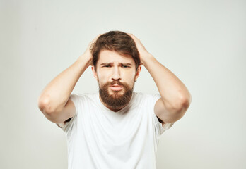 Naklejka premium bearded man in a white t-shirt hand gestures anger light background