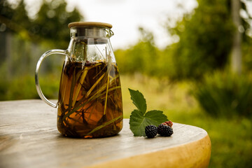 Warm glass teapot, green tea leaves and lemongrass on the wooden desk at morning.