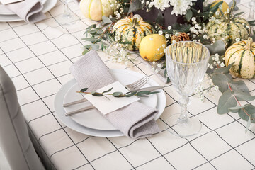 Modern table setting with card and autumn decor in restaurant
