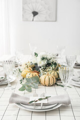 Stylish table setting with card and autumn decor in light room