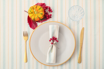 Stylish table setting with pumpkin, autumn leaves and rowan on light background