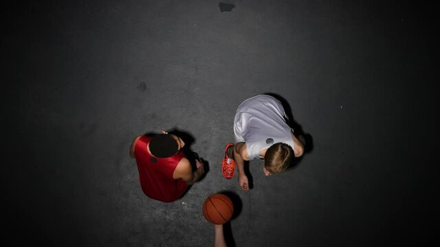 Top view of throw-in of the ball before the start of the game in basketball competition. Two opposing players jumping for possession of the ball. Slow motion.