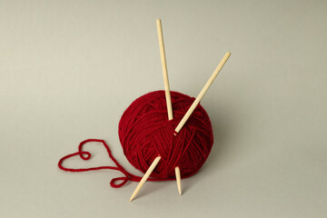 Ball of yarn with knitting needles on light gray background