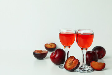 Plum brandy shots and ingredients on white background