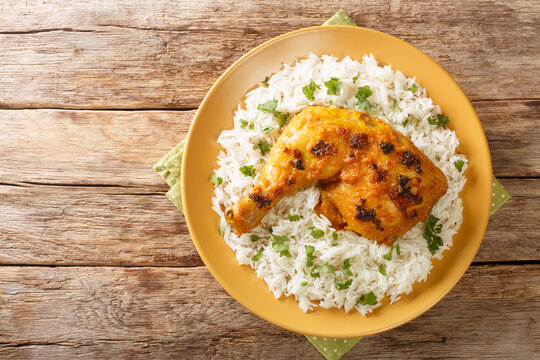 Malaysian Ayam percik or roasted spiced chicken is a grilled chicken dish that is cooked with rich coconut gravy served with rice close up in the plate on the table. Horizontal top view from above