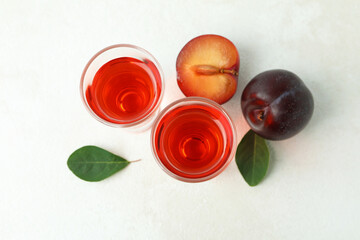 Plum brandy shots and ingredients on white textured table
