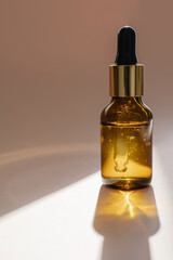 A brown bottle of serum against the beige background..