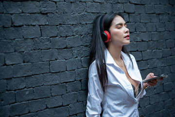 Happy cheerful Asian woman wearing wireless headphones listening to music