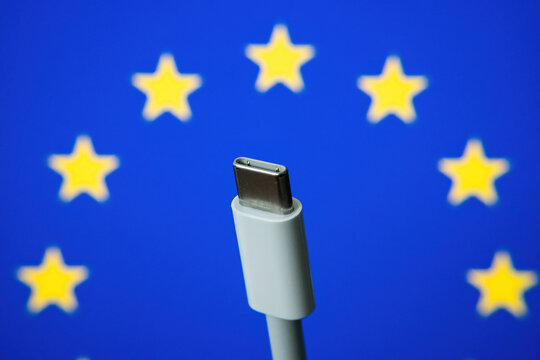 Concept for EU law to force USB-C chargers for all phones. EUROPEAN UNION flag and USBC universal charging cable as a standard for small electronic devices. Selective focus.
