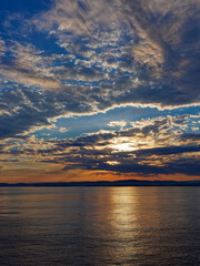 Obraz premium Sunrise over the rugged West Norwegian Coast with the low clouds being tinged orange and yellow by the rising sun on a calm Summers Morning.