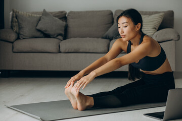 Fototapeta na wymiar Woman stretching on yoga mat at home