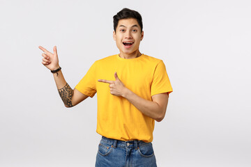 Excited, happy smiling asian young millennial man, wear yellow t-shirt, jeans, smiling astonished,...