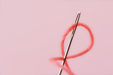 Close-up of sewing needle eye with pink thread