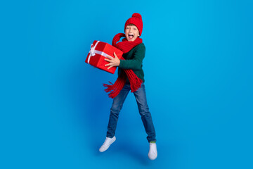 Full length body size photo boy jumping keeping xmas present isolated bright blue color background