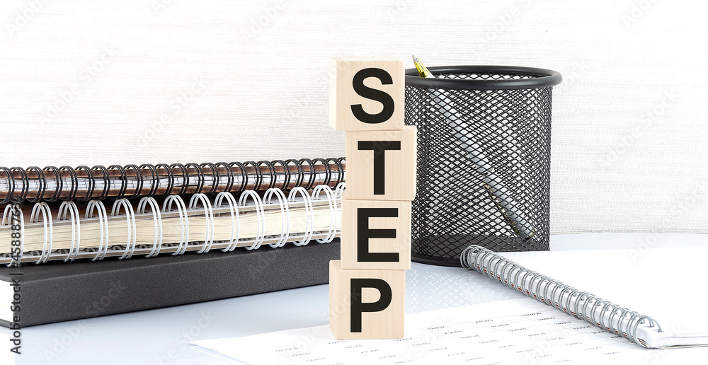 Poster step text on wooden block with notebooks on white background