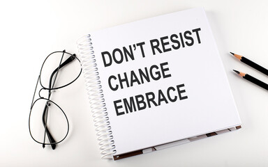 Notepad with text DON'T RESIST CHANGE EMBRACE . White background. Business concept