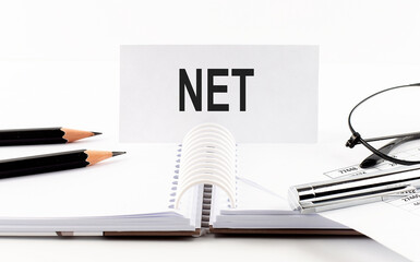 Text NET on paper card,pen, pencils,glasses,financial documentation on table - business concept