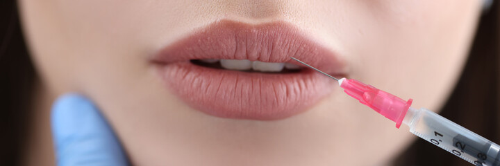 Cosmetologist makes injection to patient lips for augmentation