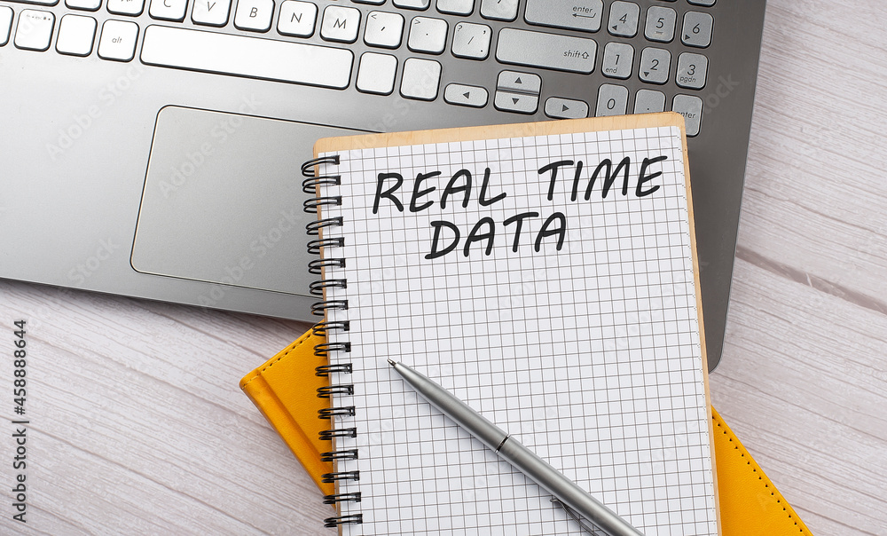 Poster real time data text written on a notebook on the laptop