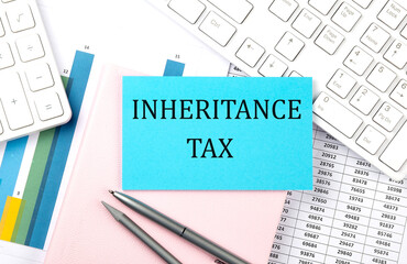 INHERITANCE TAX text on blue sticker on chart with calculator and keyboard,Business