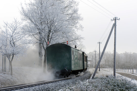 Sich entfernender Zug einer Schmalspurbahn in frostiger Winterlandschaft 