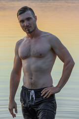 Sexy Portrait of Handsome Topless Male Model on the Beach. 
Summer Relax. Portrait Of Athletic Sexy Man With Muscular Body Handsome Fitness Male Model on Sunset.