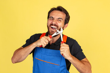 Half-length portrait of smiling young bearded man, male auto mechanic or fitter wearing blue work...
