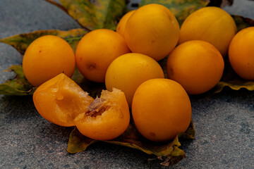 golden yellow ripe plums on autumn maple leaf on granite table top outdoors. Healthy vegan food....