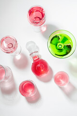 drinks for the festive table: pink champagne, liqueur, green martini. Top view on a white table. Bright fashionable light 