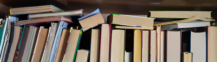 Background with books standing and lying on the shelf. Close-up. - obrazy, fototapety, plakaty