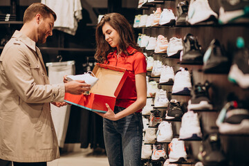 Young man choosing sneakers at sportswear shop