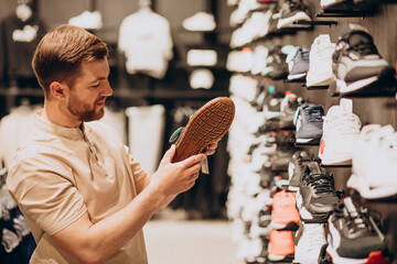 Young man choosing sneakers at sportswear shop