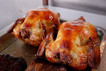 Chicken roasted in Thai style on metal tray and blur bright background, favorite home made style in Thailand.