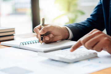 Close up Businessman and partner using calculator and laptop for calaulating finance, tax, accounting, statistics and analytic research concept