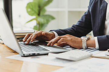 Close up of businessman or accountant working on laptop computer for calculate business data, accounting document and calculator at office, business concept