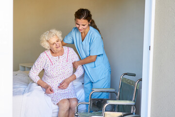Krankenschwester hilft Seniorin im Bett beim Aufstehen