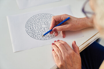 Senioren Hände mit Stift beim Labyrinth Rätsel lösen