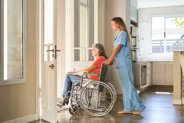 Pflegekraft schiebt eine gelähmte Seniorin im Rollstuhl