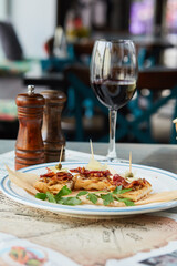bruschetta on a wooden table in a white plate and a glass of red wine