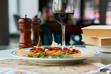 bruschetta on a wooden table in a white plate and a glass of red wine
