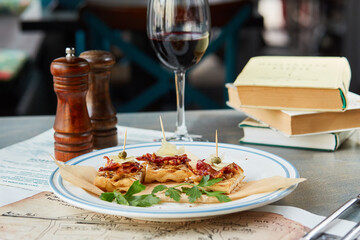 bruschetta on a wooden table in a white plate and a glass of red wine