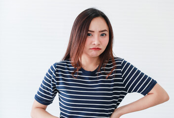 Studio portrait shot of Asian young angry mad crazy grumpy upset serious stress aggressive sad female model in casual clothing staring look at camera posing holding hand on waist on white background