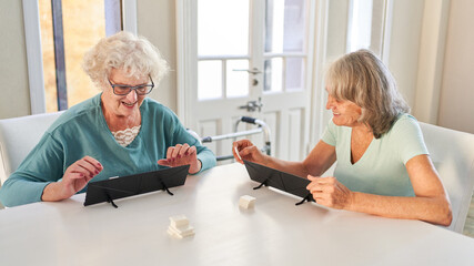 Zwei Senioren spielen gemeinsam Rummikub in Altersheim