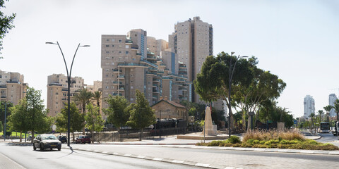 the small Ottoman era Turkish Train Station in Beer Sheva in Israel is surrounded by modern high rise buildings and avenues with a pale blue sky background