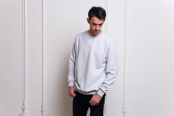 Fashion and people concept - young brunette man in gray clothes and jeans over white wall background